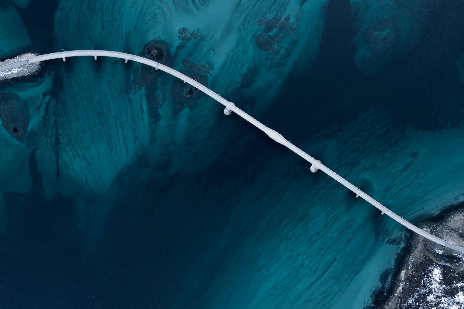 Aerial view of a bridge crossing deep blue water